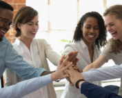 Various employees happily put their hands together in a cheer representing their contentment in the workplace and how this results in great employer branding.
